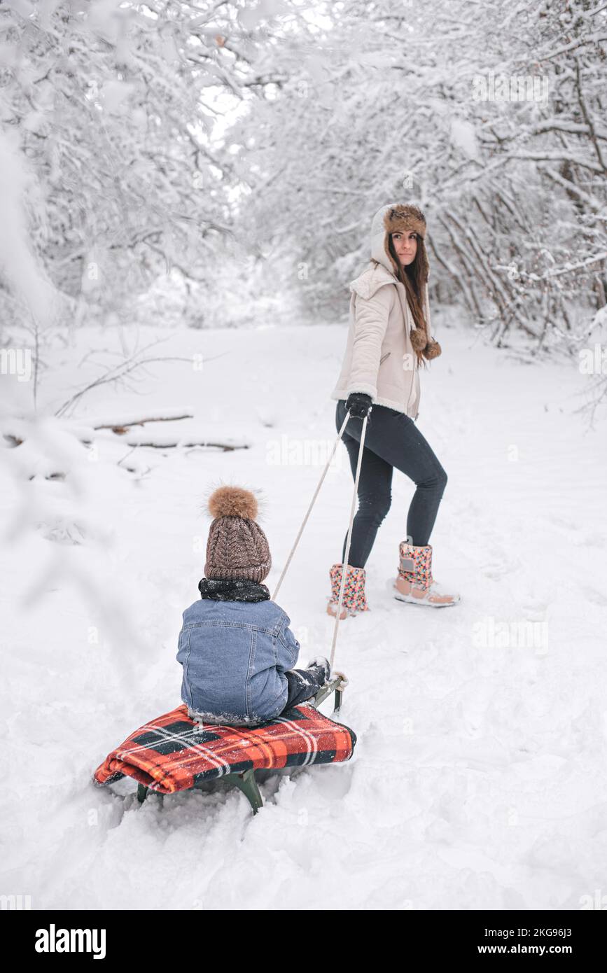 Maman et son fils marchent dans la neige dans la forêt d'hiver. Banque D'Images