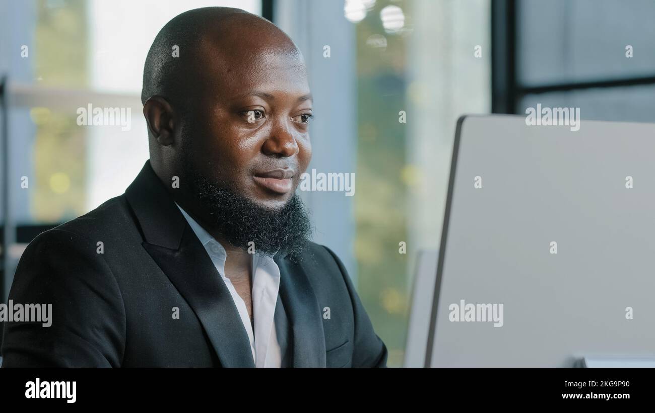 Homme d'affaires africain adulte heureux plus grand gars satisfait avec l'ordinateur de saisie d'application sur ordinateur portable dans le bureau souriant recommander bon choix bonne idée signe Banque D'Images