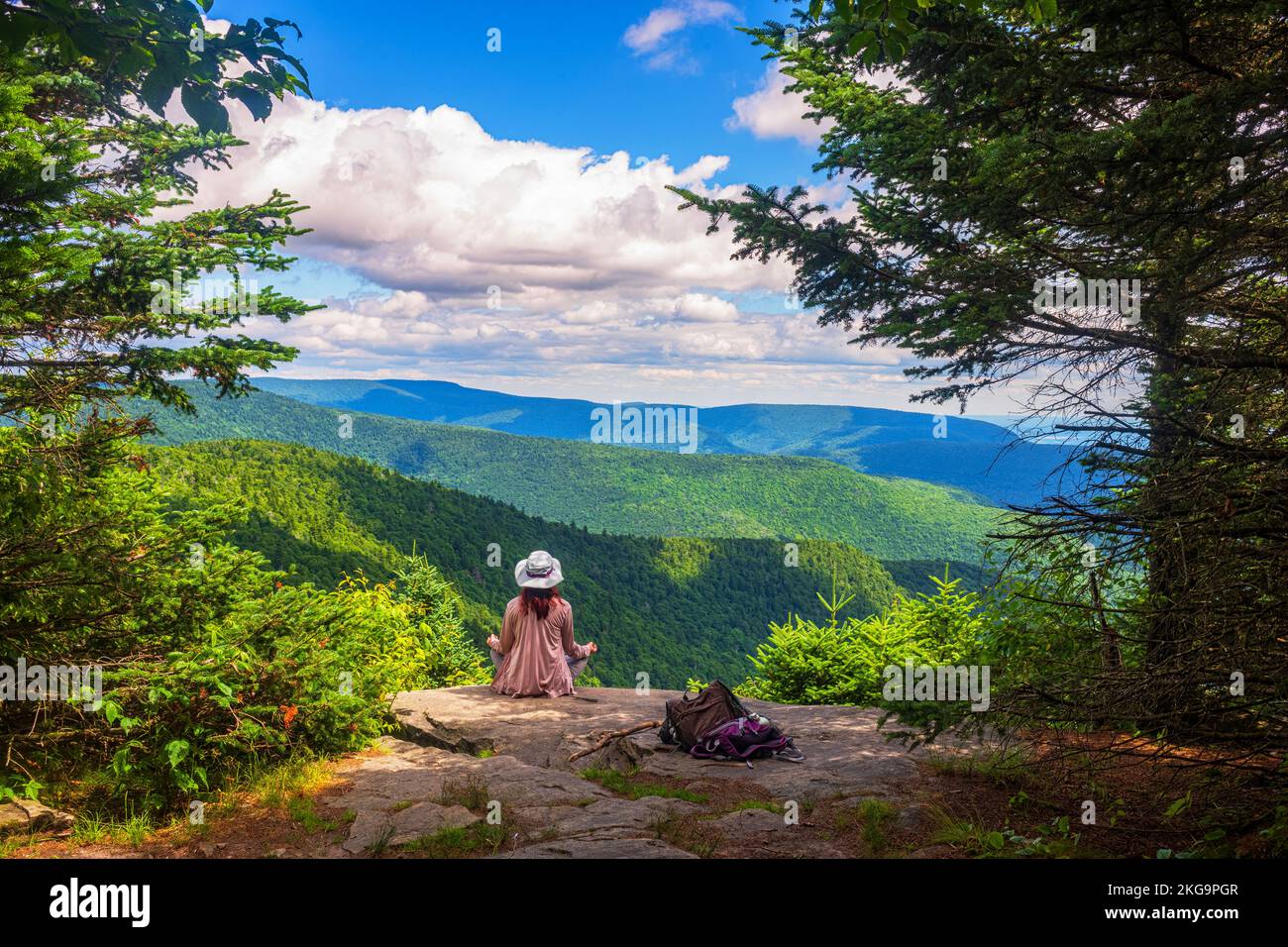 Une femme non identifiable est assise dans la posture de yoga Sukhasana au bord d'une falaise de West Kill Summit dans les montagnes Catskill de l'État de New York pendant Banque D'Images