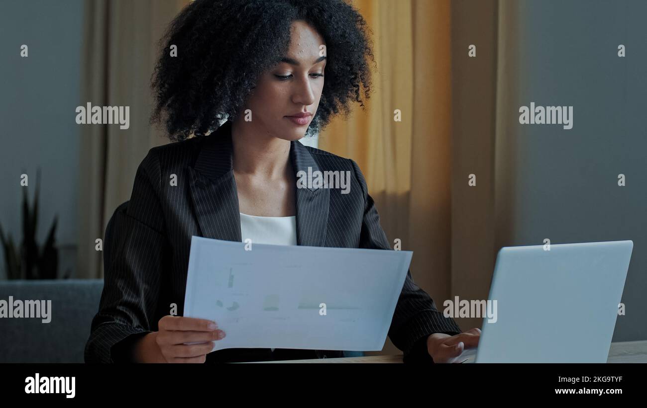 Femme d'affaires enseignante africaine travailler avec des documents graphiques à la maison de bureau vérifier la documentation entrer les données financières à ordinateur portable de traitement en ligne Banque D'Images