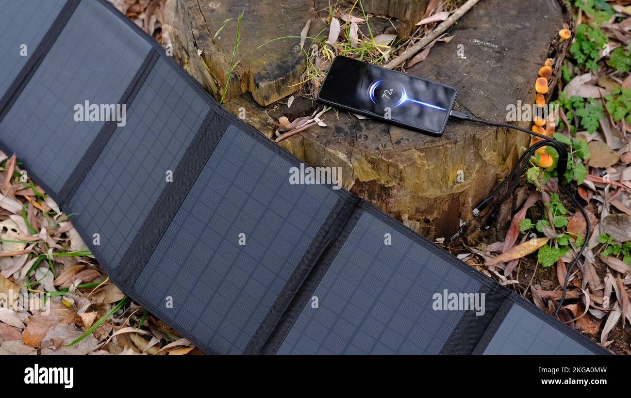 panneau solaire portable de charge smartphone par câble multi-usage, banque d'énergie, montres, ordinateurs portables nature arrière-plan. Énergie propre pour l'utilisation dans le camping ou un Banque D'Images