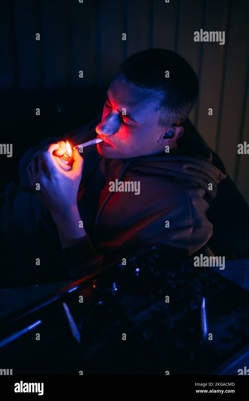 Portrait d'un homme au néon qui fume un joint. Guy fume joint, marijuana, drogues cbd et thc Banque D'Images