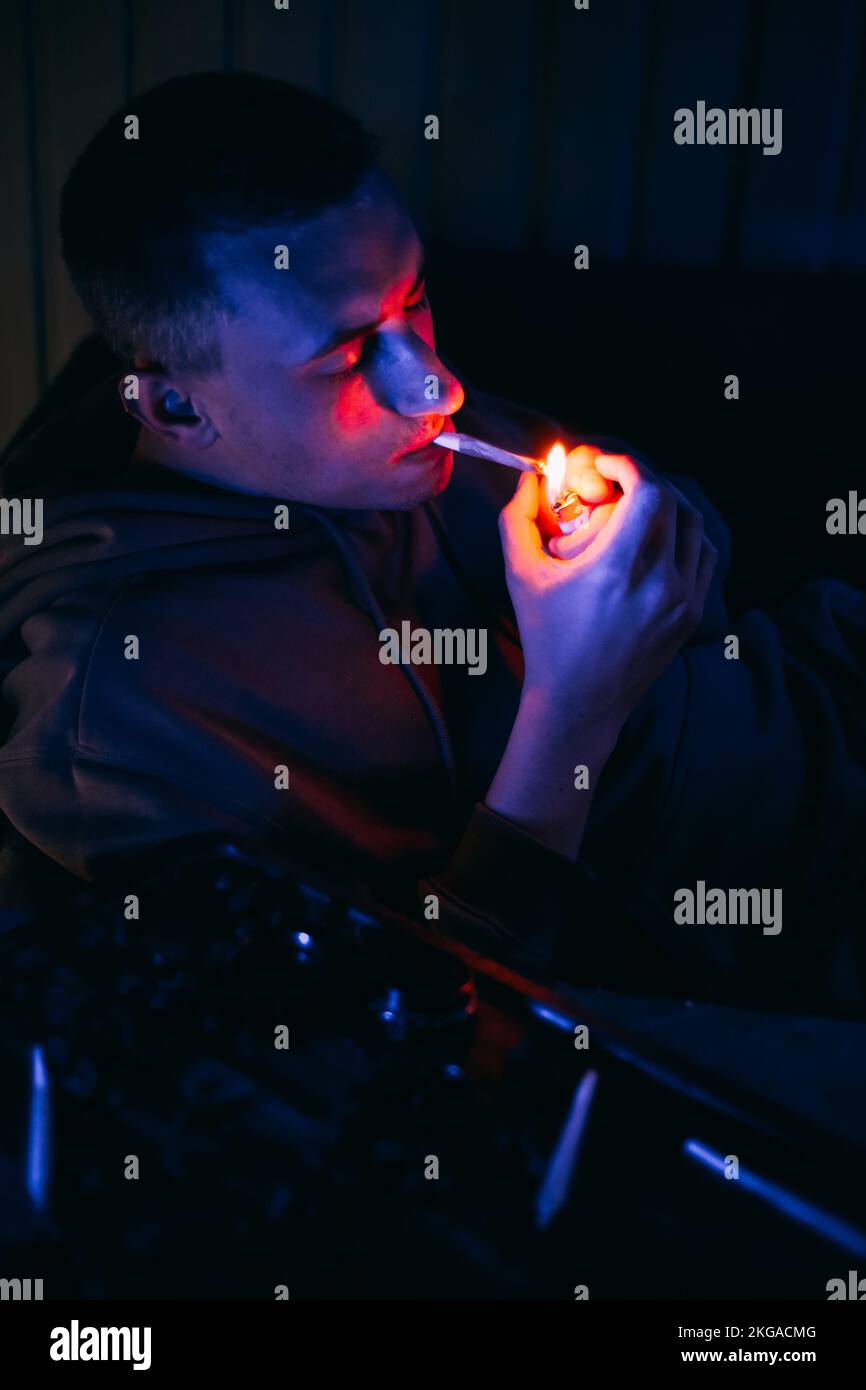 Portrait d'un homme au néon qui fume un joint. Guy fume joint, marijuana, drogues cbd et thc Banque D'Images