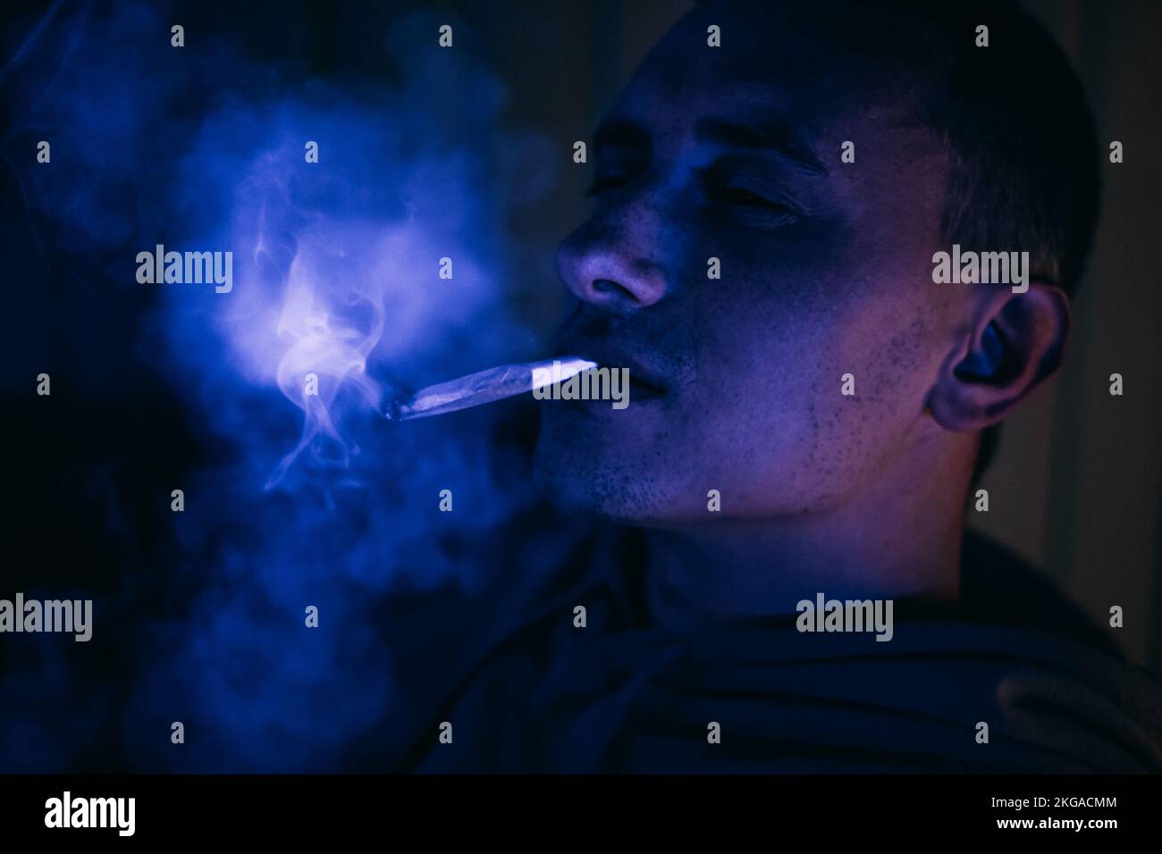 Portrait d'un homme au néon qui fume un joint. Guy fume joint, marijuana, drogues cbd et thc Banque D'Images