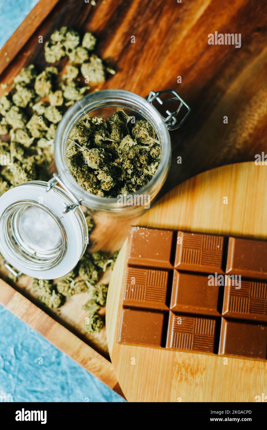 Chocolat avec de la marijuana sur le fond d'une table en bois et des cônes de marijuana. CBD et THC, sativa et indica. herbe de marijuana dans la nourriture Banque D'Images