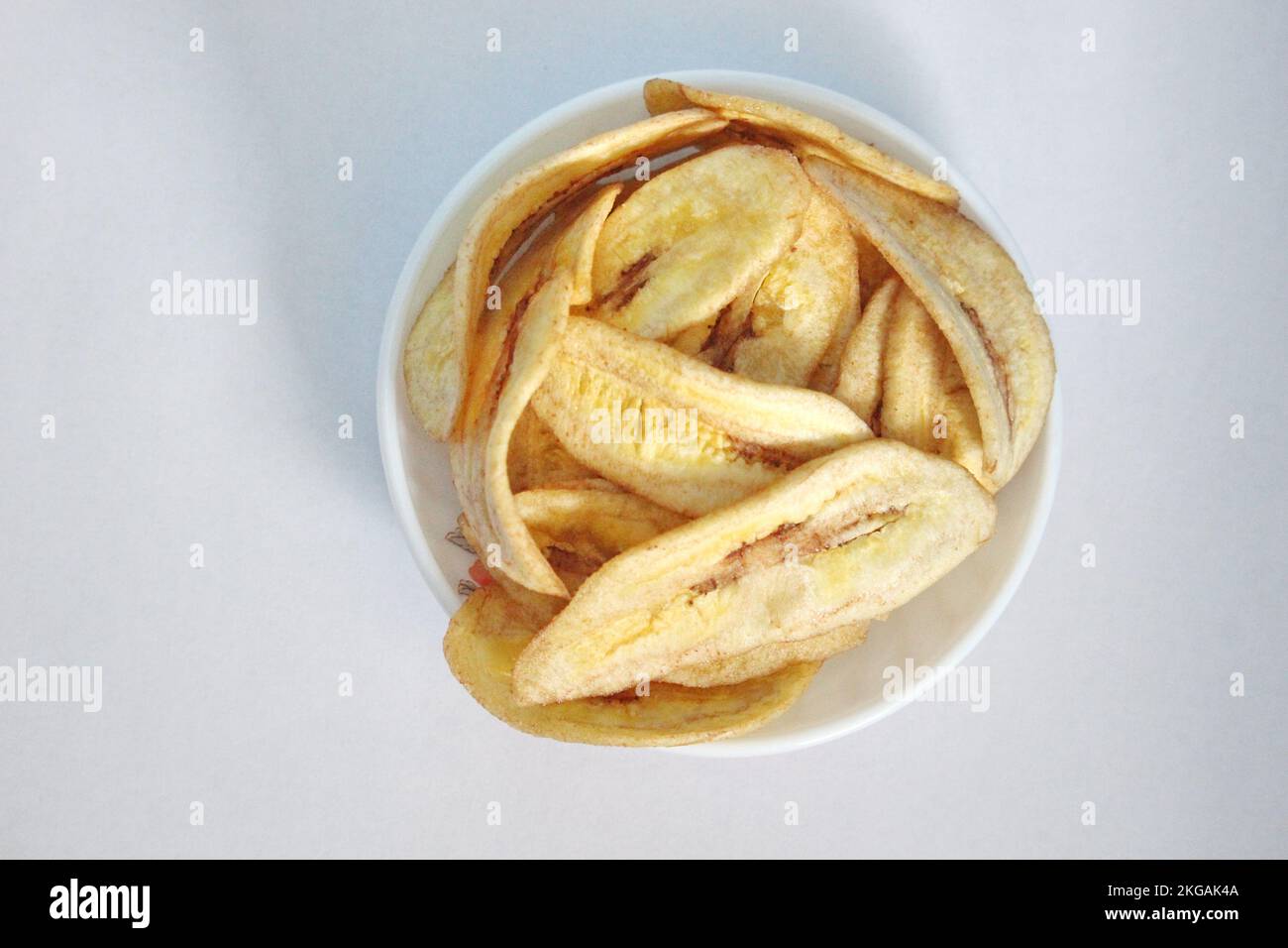 Chips de banane dans une assiette blanche sur un fond blanc prêt à la vente Banque D'Images