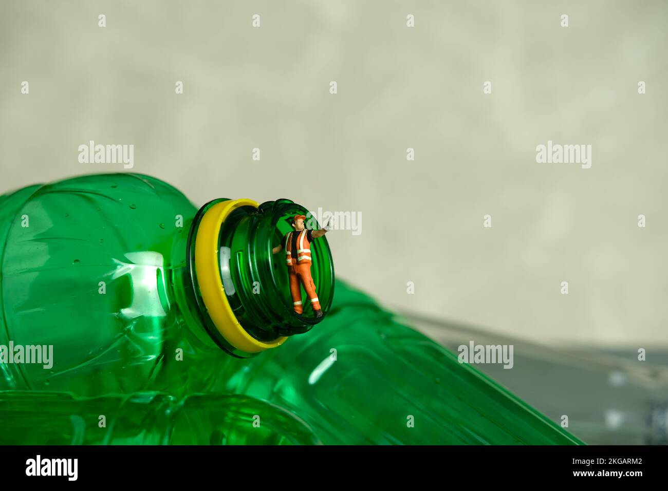 Photographie miniature de personnage de jouet de personnes. Un employé de nettoyage avec une poubelle se trouvant entre les bouteilles de boisson en plastique. Photo d'image Banque D'Images