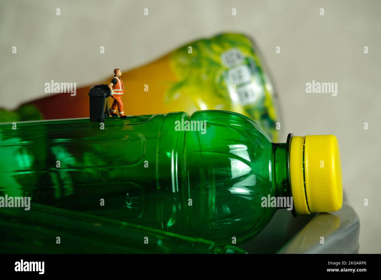 Photographie miniature de personnage de jouet de personnes. Un employé de nettoyage avec une poubelle se trouvant entre les bouteilles de boisson en plastique. Photo d'image Banque D'Images