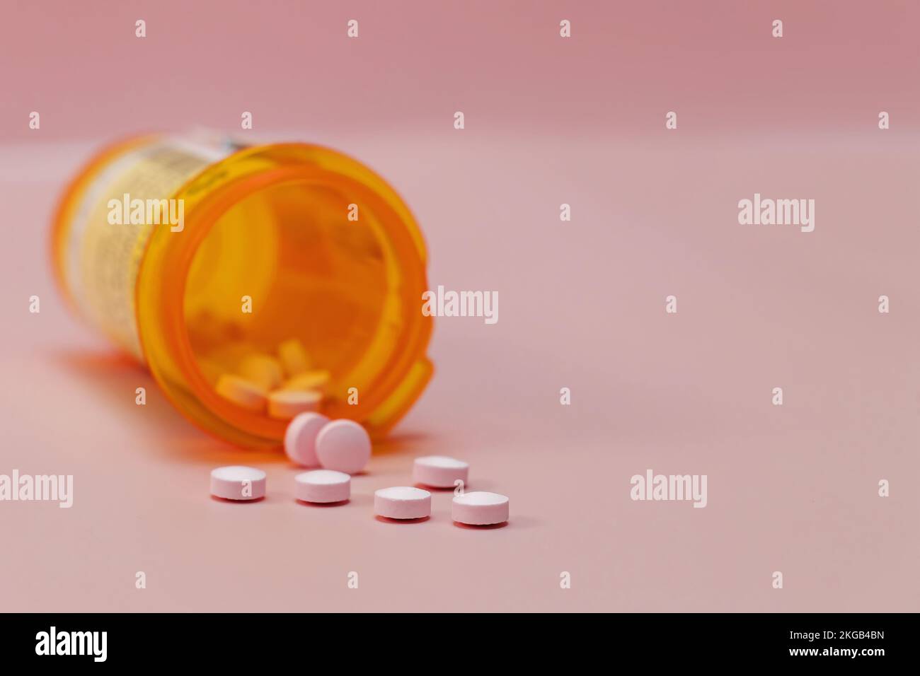 Comprimés en plastique orange bouteille gros plan, médicament prescrit sur fond rose. Mise au point sélective. Banque D'Images