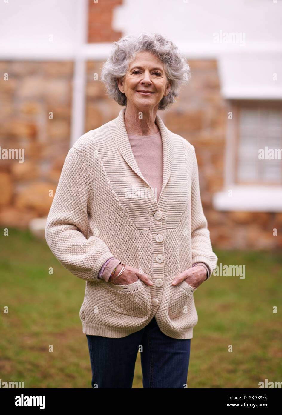 Vieillissement avec grâce et poise. Portrait d'une femme âgée debout à l'extérieur de sa maison. Banque D'Images
