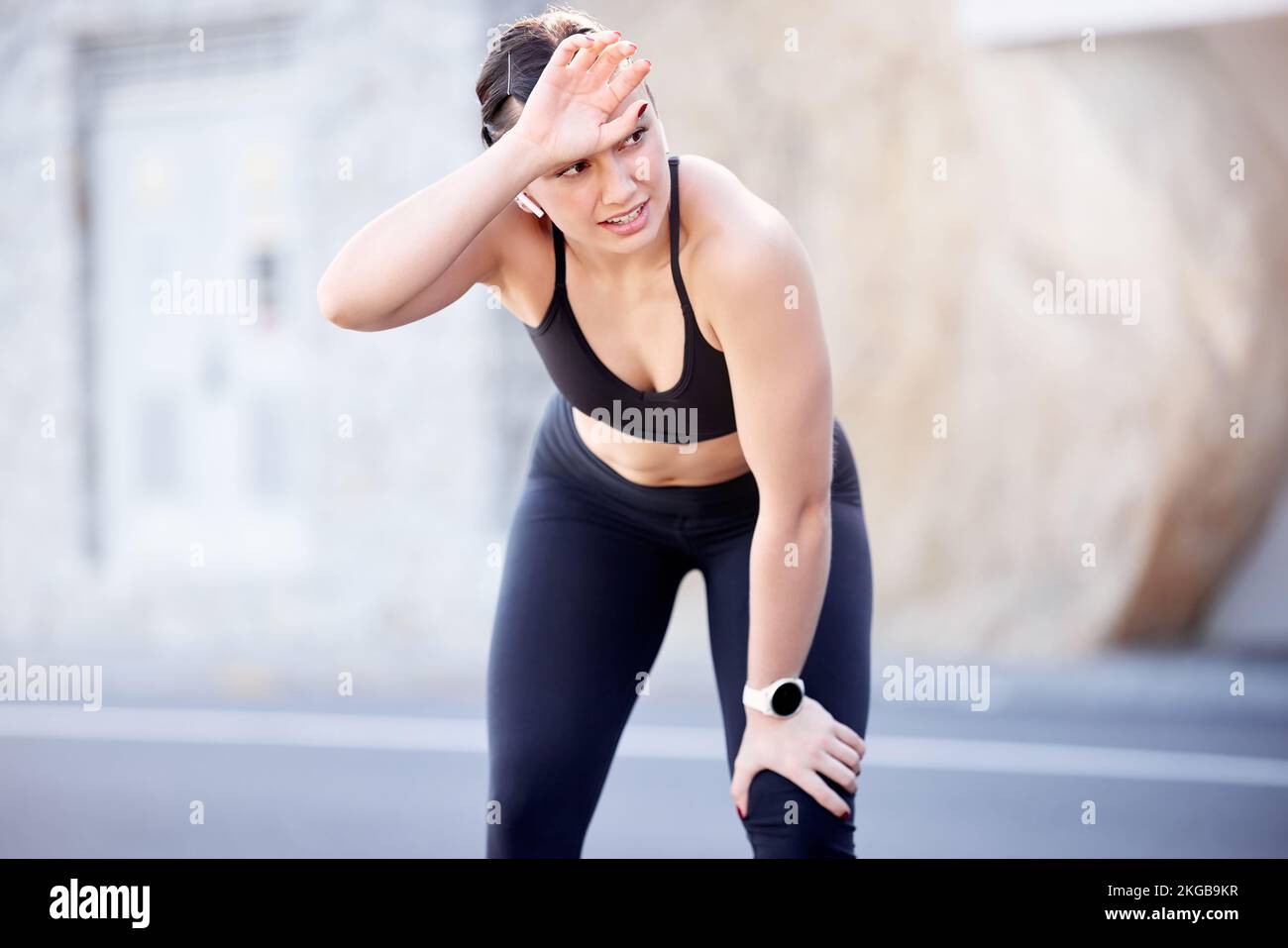 Fitness, fatiguée et transpirante avec une femme de sport essuyant son front après avoir été en plein air dans la ville pour le cardio. Route, exercice et entraînement avec une femme Banque D'Images