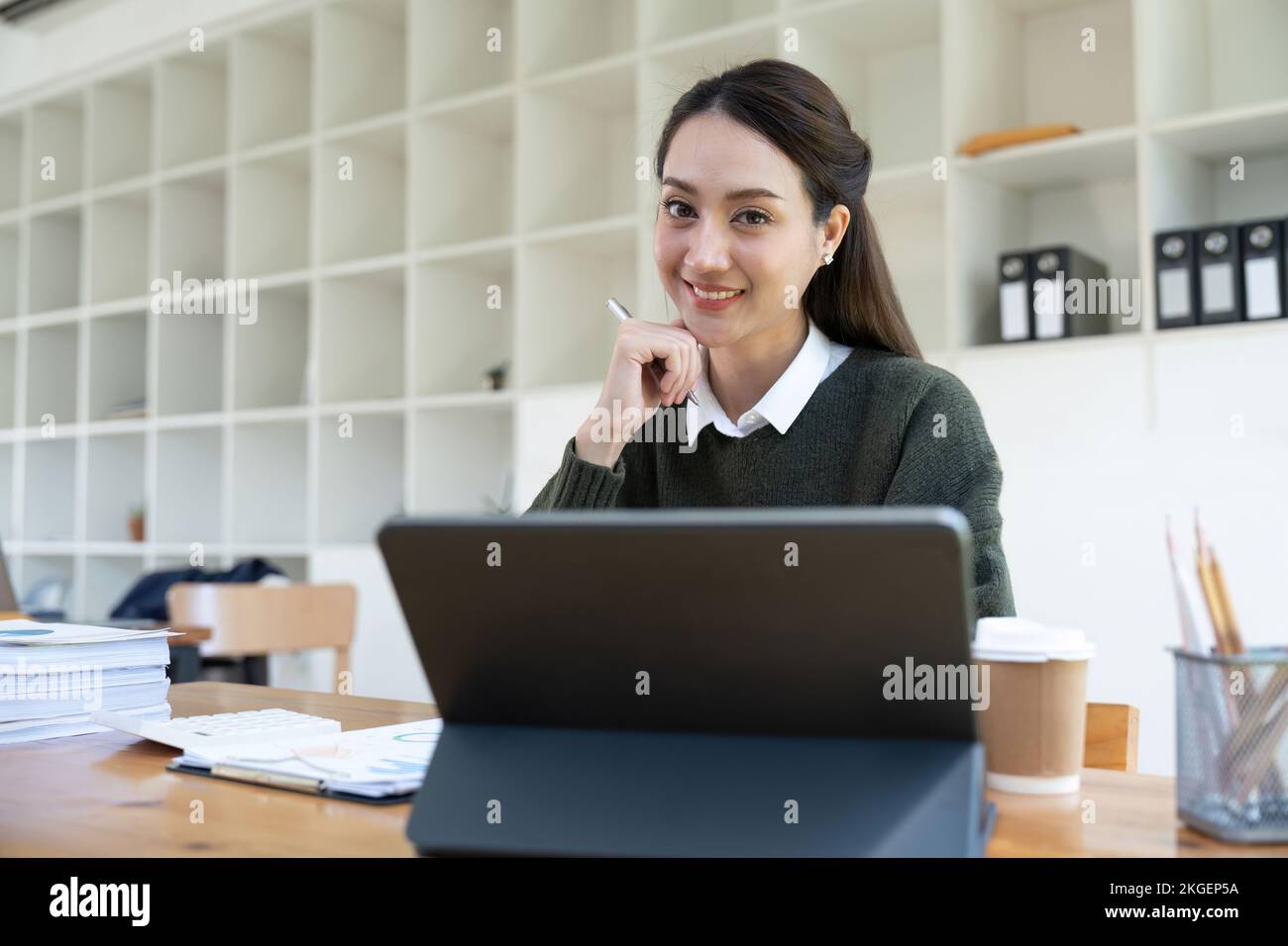 Portrait d'une femme asiatique souriante utilisant un ordinateur portable pour l'analyse de la paperasserie financière. Banque D'Images