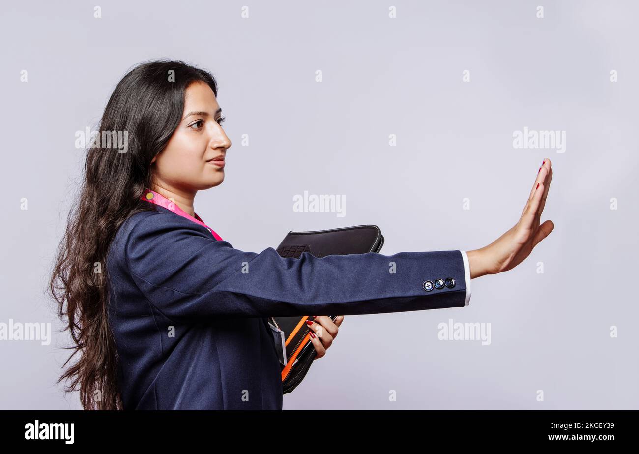 Cadre professionnel féminin indien dans une tenue formelle donnant un geste d'arrêt ferme - lieu de travail assertif véhiculant l'affirmation de soi et l'autorité. Banque D'Images