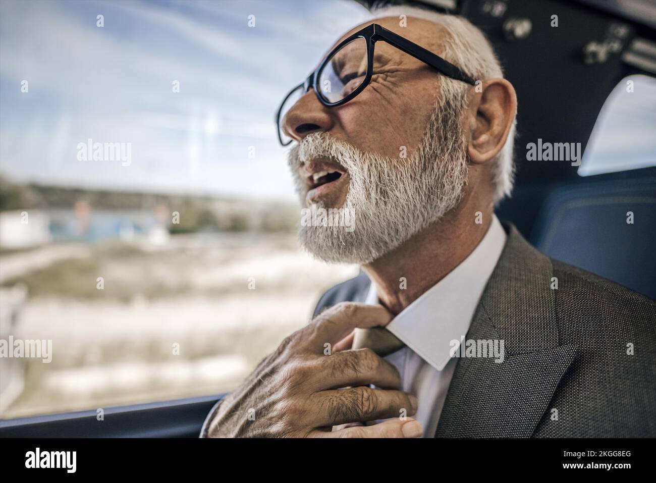 Gros plan d'un homme âgé qui ressent une douleur inconfortable lorsqu'il est assis dans le train. Le grand muter fait face ayant un sérieux problème de santé Banque D'Images