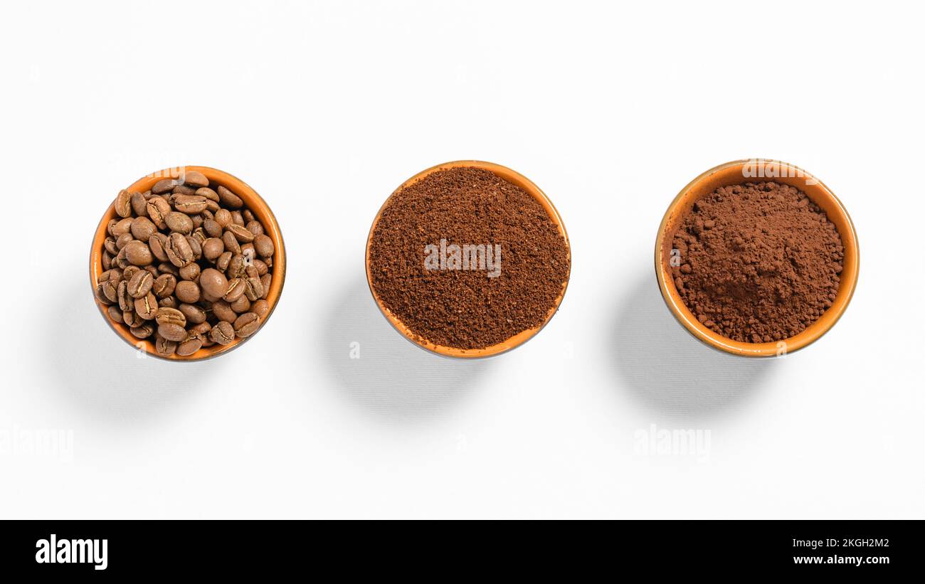 Trois tasses avec grains de café, café moulu et cacao à titre de comparaison, boisson énergétique au café, fond blanc et tasses avec différents cafés. Banque D'Images