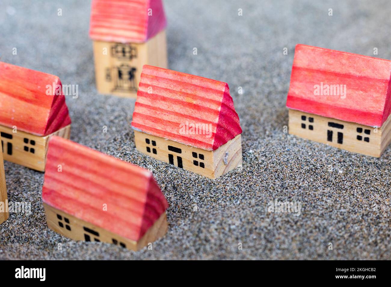 Petites maisons de jouets en bois. Construire des maisons sur le sable. Jeu pour enfants. Cinq cottages avec toit rouge sur sol gris. Village de modélisation. Construction et Banque D'Images