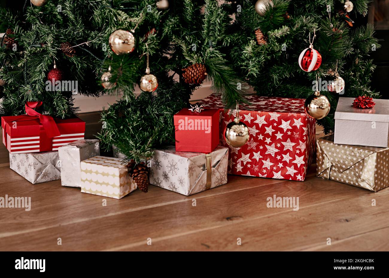 Noël, plancher et boîte de cadeau par arbre pour la fête, la saison des fêtes et la fête. Noël, surprise et gratitude avec le présent sur le sol de la salle de séjour Banque D'Images