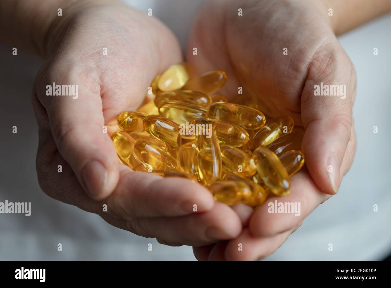 Les capsules d'huile de foie de morue tombent dans les paumes de la femme mature Banque D'Images