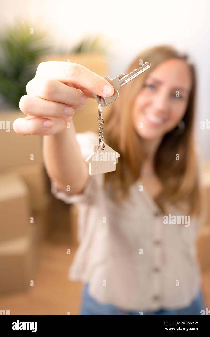 Bonne jeune femme souriant avec le nouveau porte-clés de la maison avec maison en bois réel état vertical tourné Banque D'Images