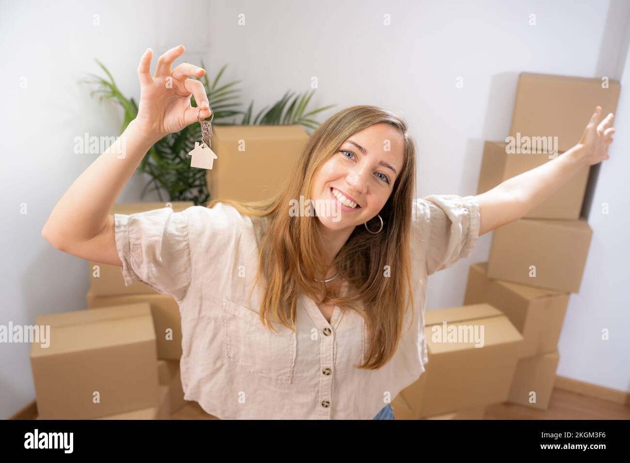 Bonne jeune femme souriant avec le nouveau porte-clés de la maison en forme d'une maison en bois véritable état Banque D'Images