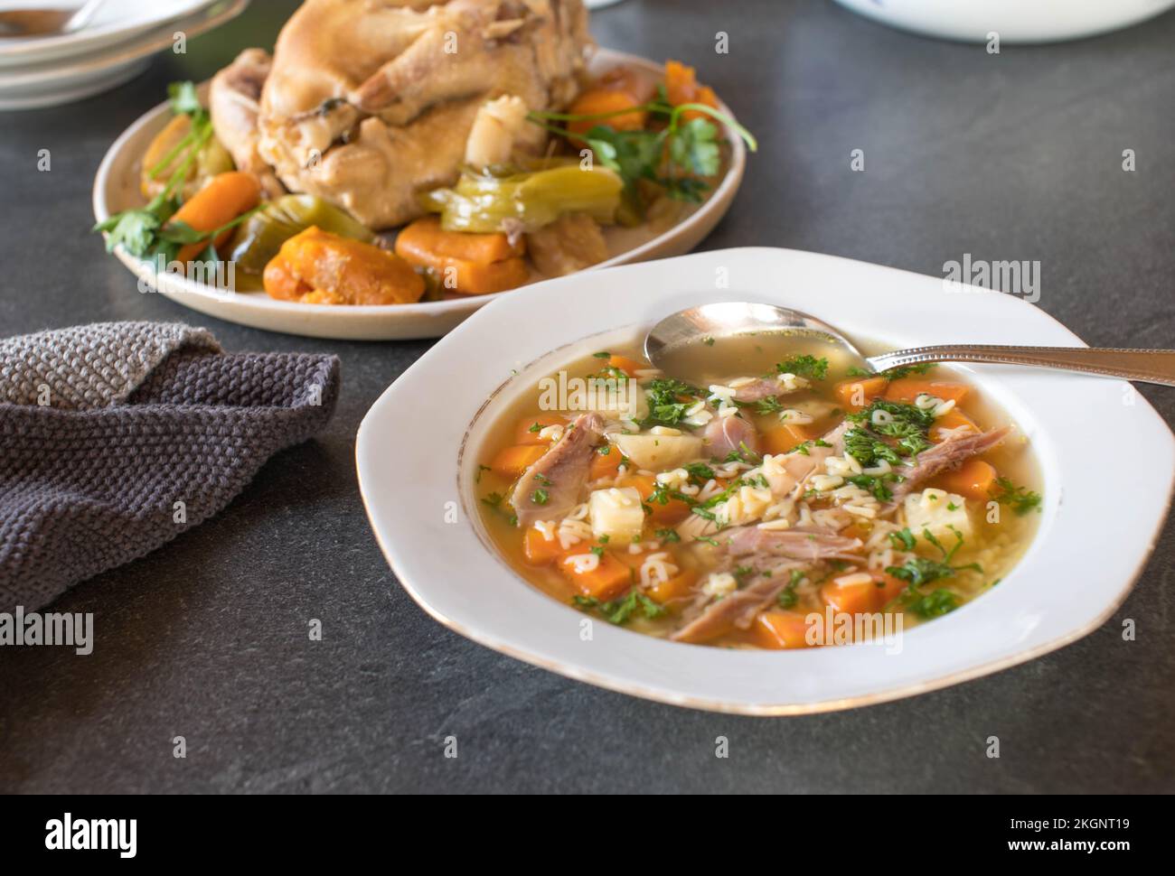 Assiette avec soupe de nouilles de poulet fraîchement cuites cuisinées et pâtes à l'alphabet sur une table de cuisine Banque D'Images