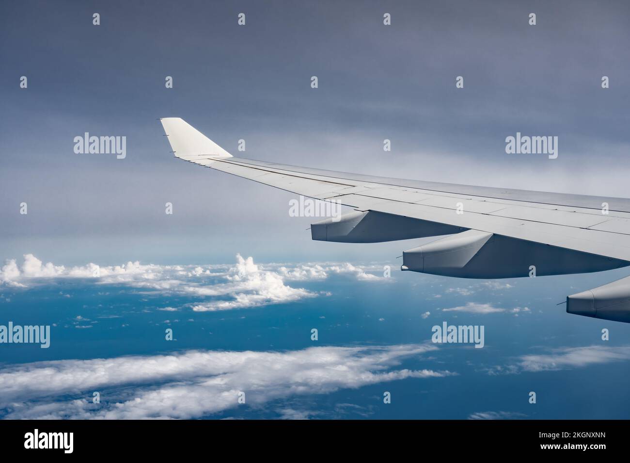 Aile de l'avion au-dessus de la surface plate des nuages moelleux avec la douce lumière du soleil du soir. Copier l'espace. Banque D'Images