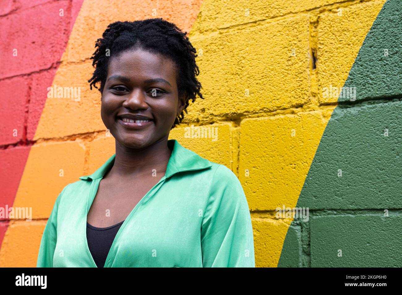 Jeune femme souriante devant un mur coloré Banque D'Images