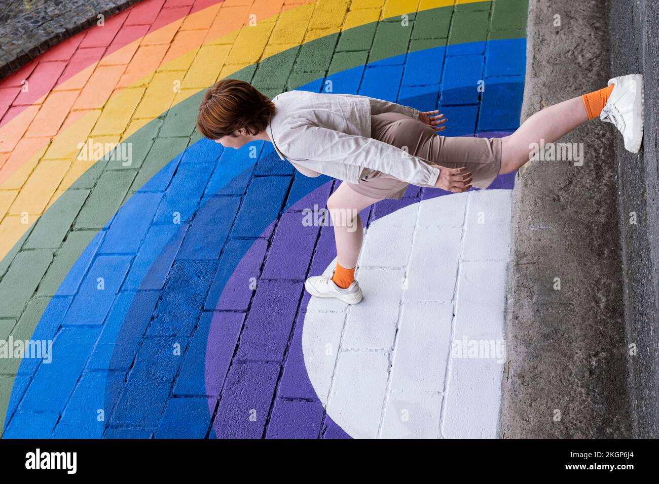 Jeune femme qui marche sur un mur de couleur arc-en-ciel Banque D'Images
