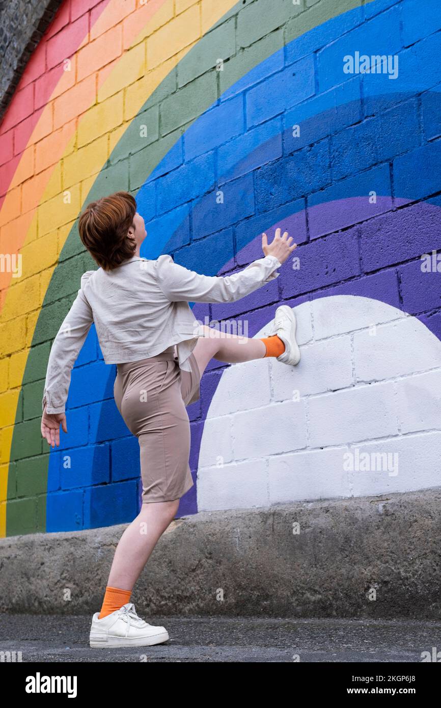 Femme qui marche sur un mur de couleur arc-en-ciel Banque D'Images