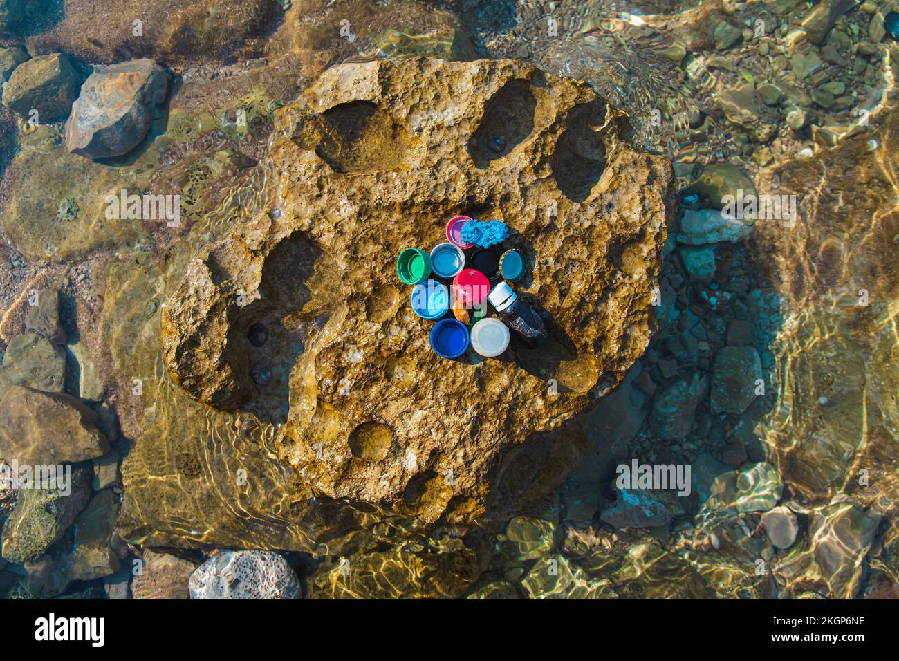 Bouchons de bouteille et déchets sur le rocher à la plage Banque D'Images