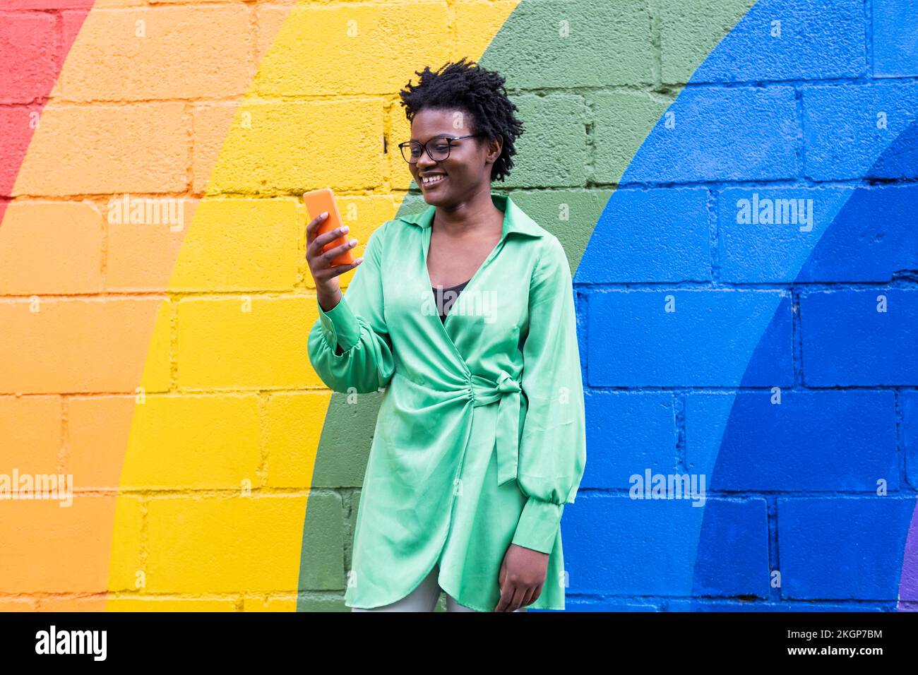 Jeune femme heureuse utilisant un smartphone devant un mur coloré Banque D'Images