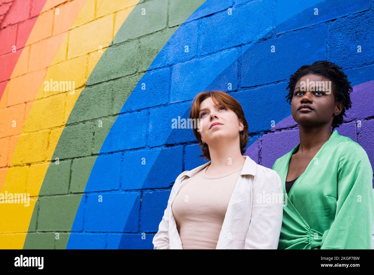 Jeune femme attentionnés avec une amie devant un mur de couleur arc-en-ciel Banque D'Images