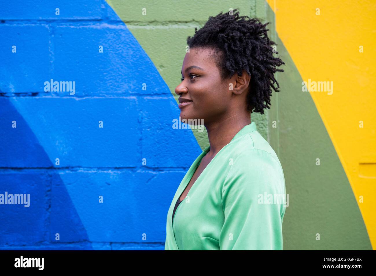 Jeune femme souriante devant un mur coloré Banque D'Images