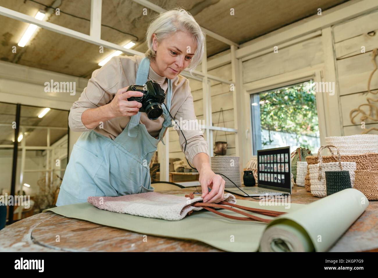 Artisan souriant tenant un sac d'organisation de caméra sur établi en atelier Banque D'Images