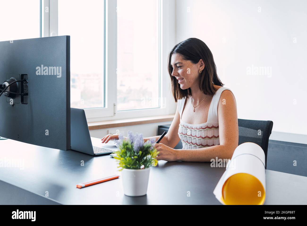 Jeune architecte souriant travaillant sur un ordinateur portable au bureau Banque D'Images