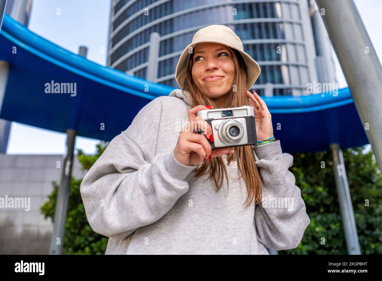 Femme souriante tenant l'appareil photo devant le bâtiment Banque D'Images