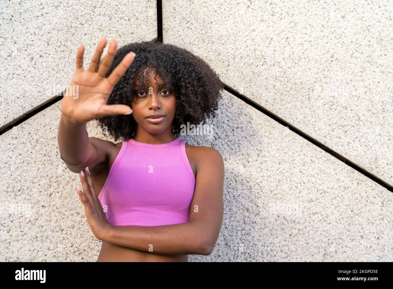 Une jeune femme signe d'arrêt de gestuelle devant le mur Banque D'Images