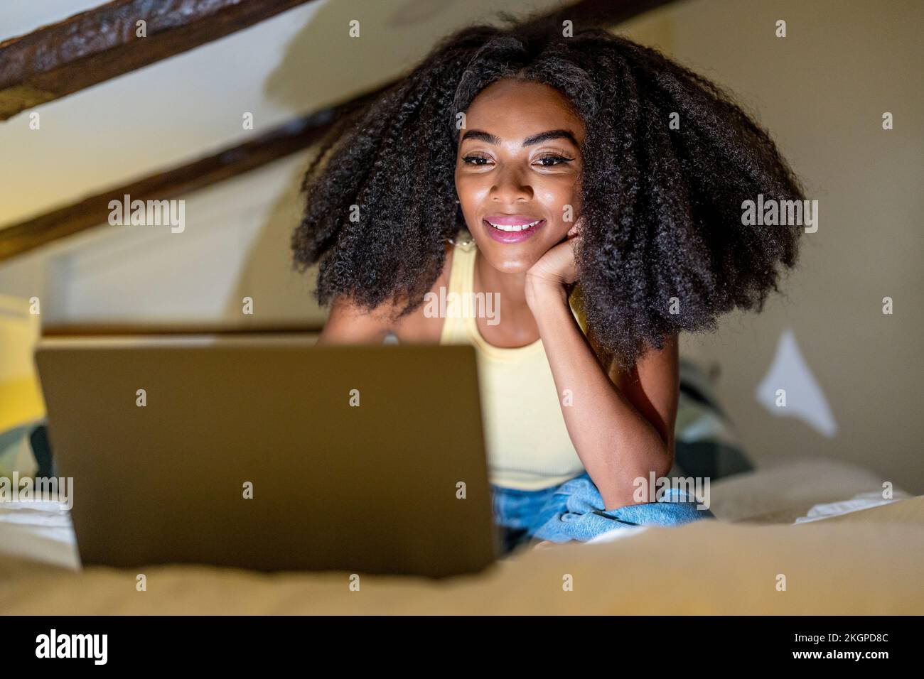 Jeune femme regardant un film sur un ordinateur portable dans la chambre Banque D'Images