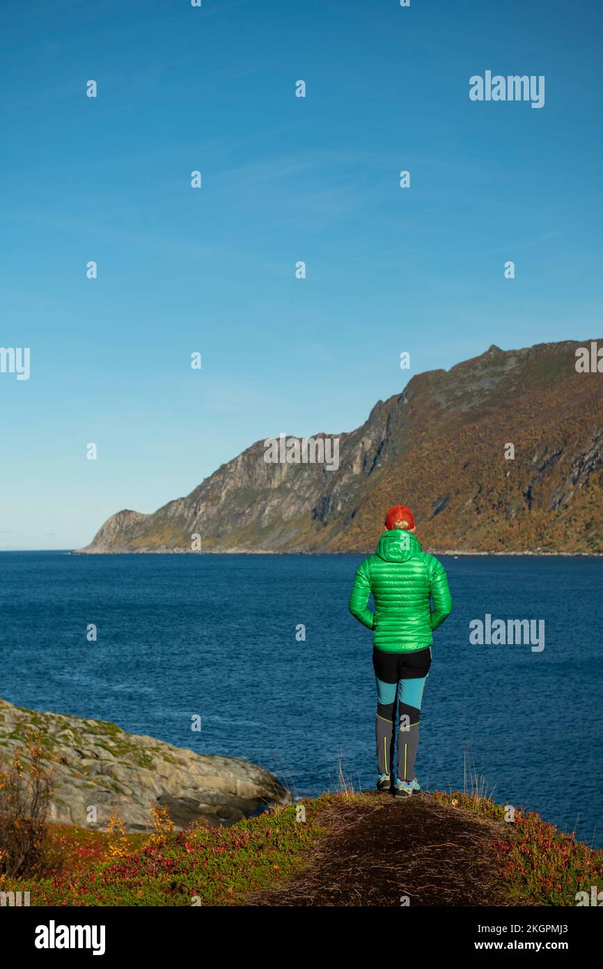 Femme en veste matelassée debout au bord de la montagne Banque D'Images