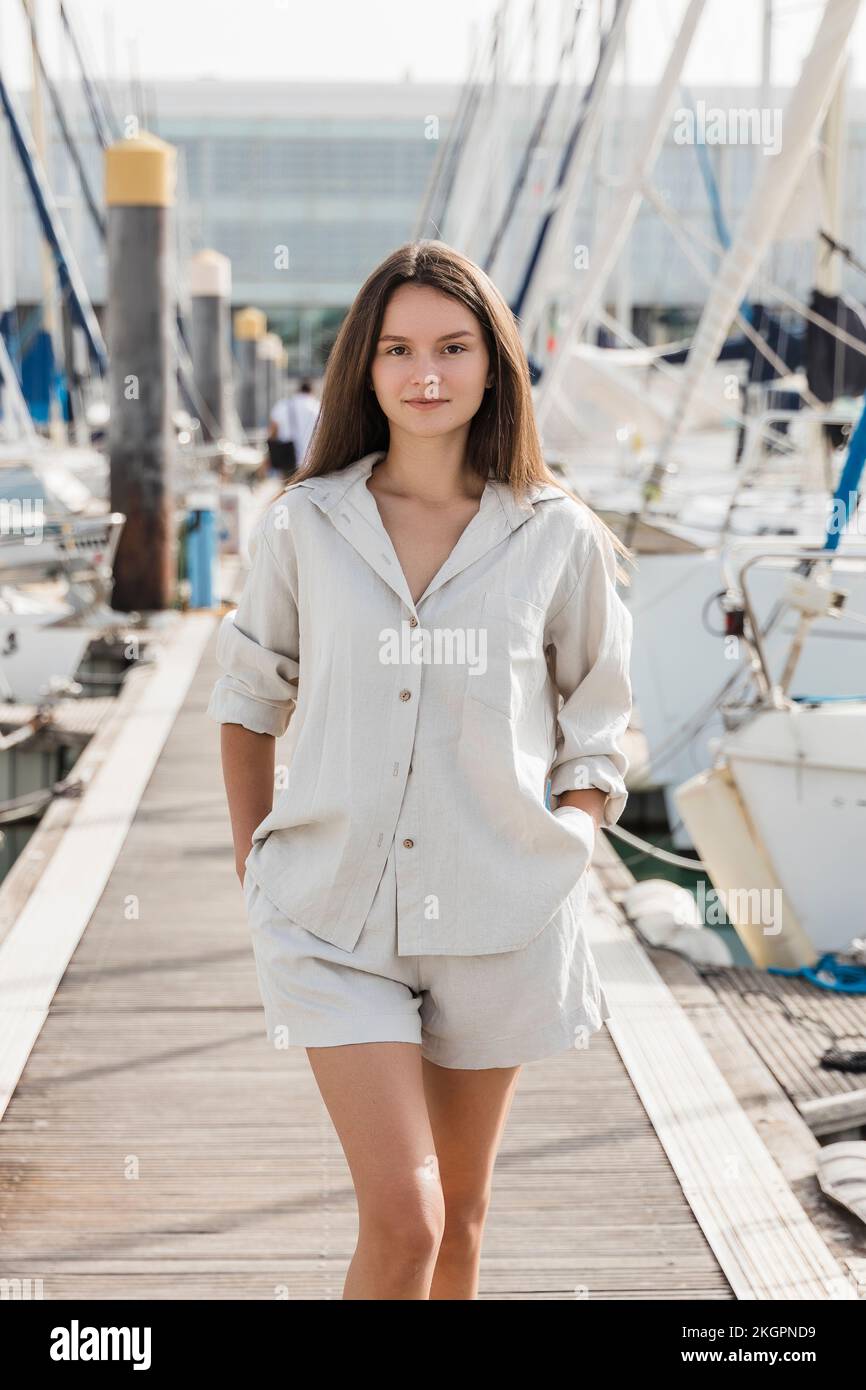 Belle femme avec les mains dans les poches marchant sur la jetée Banque D'Images