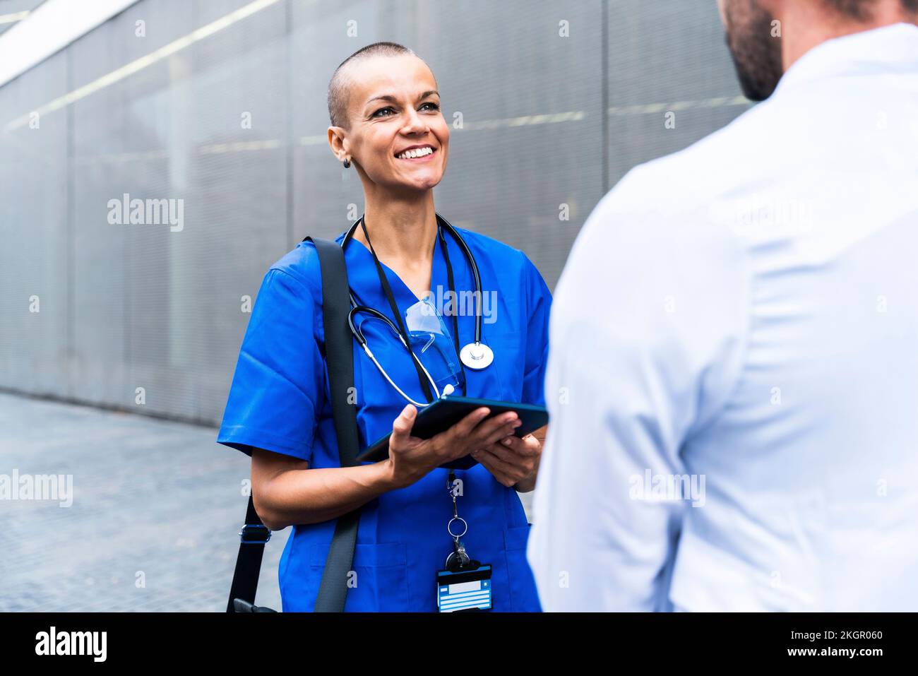 Infirmière souriante avec tablette PC parlant au médecin Banque D'Images