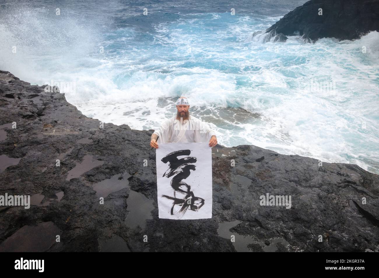Monk montrant de la calligraphie sur papier debout en face de la mer Banque D'Images