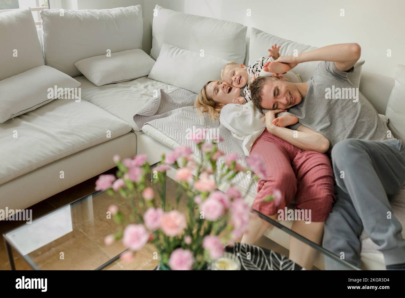 Mère et père heureux s'amuser avec leur fils sur le canapé à la maison Banque D'Images