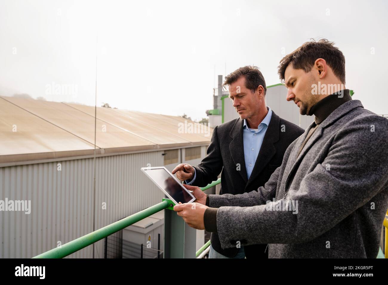 Les hommes d'affaires discutent de PC tablette à l'usine de recyclage Banque D'Images