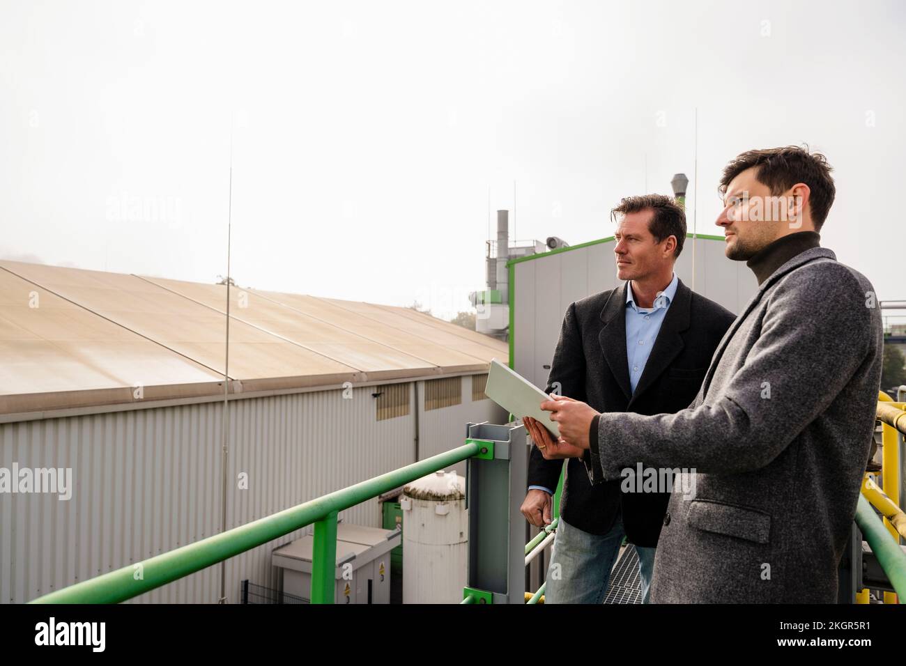 Les hommes d'affaires discutent avec les Tablet PC à l'usine de recyclage Banque D'Images