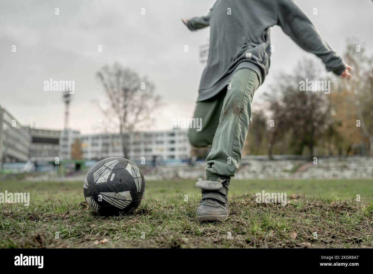 Un garçon donne un coup de pied au ballon de football sur le terrain de sport Banque D'Images