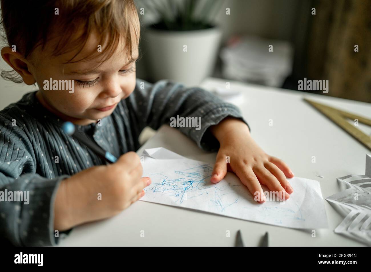 Mignon garçon avec crayon de couleur sur papier à la maison Banque D'Images