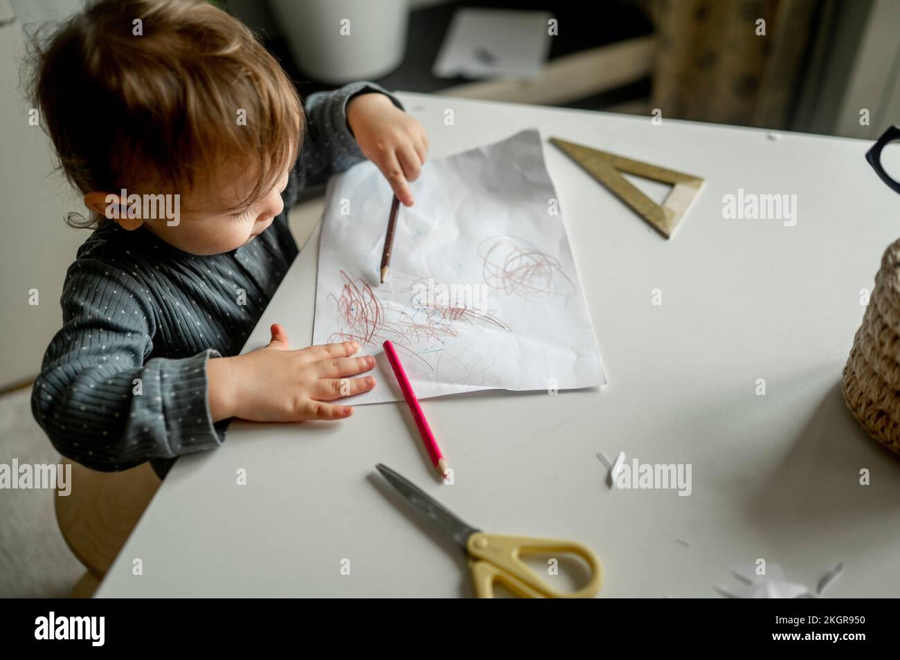 Un garçon griffonne avec un crayon sur le papier à la maison Banque D'Images