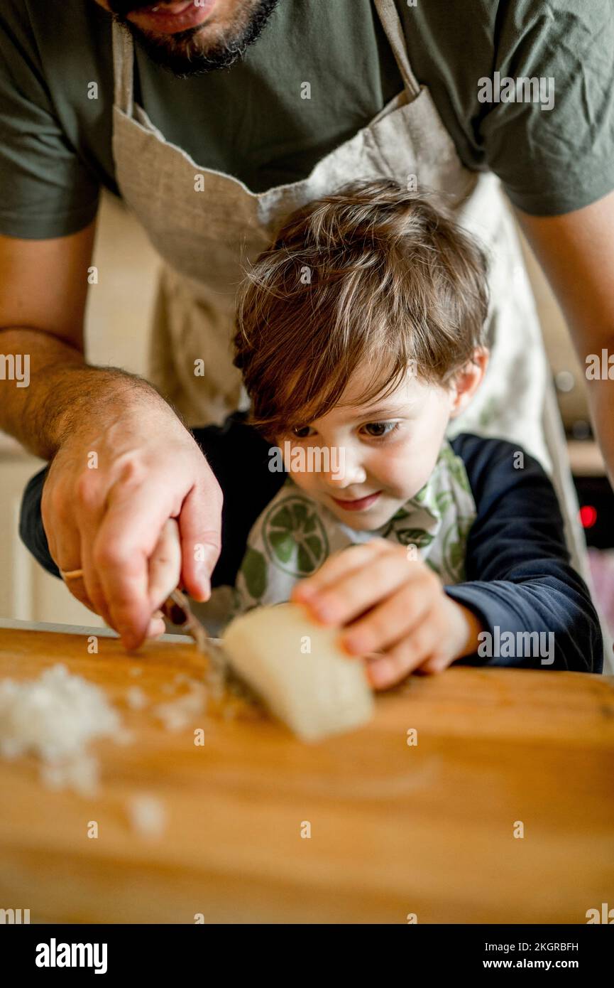 Fils apprenant à hacher l'oignon du père dans la cuisine à la maison Banque D'Images