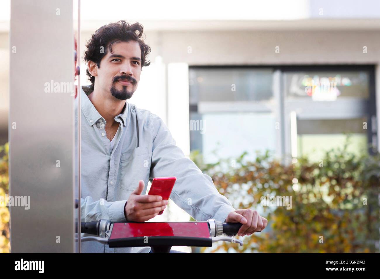 Homme attentionné avec téléphone intelligent, location de vélo à la gare Banque D'Images